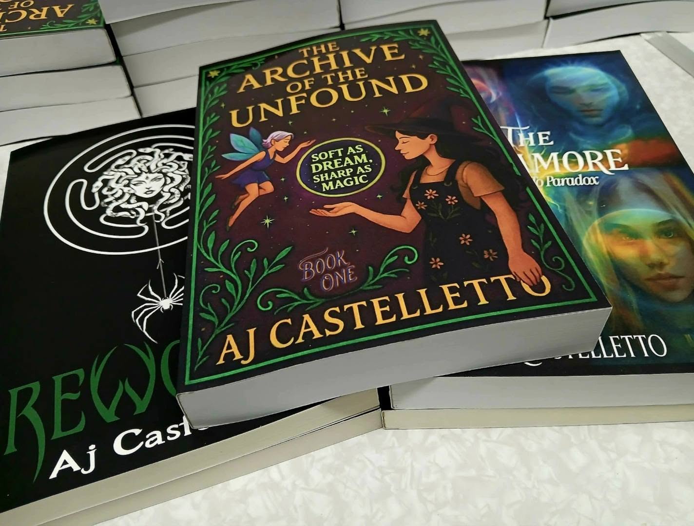 Paperbacks of Rewoven, The Archive Book 1, and The Sycamore stacked together